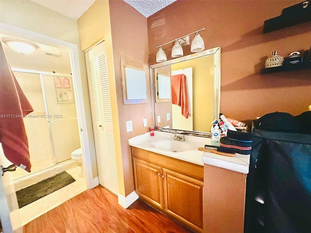 bathroom featuring walk in shower, a textured ceiling, vanity, hardwood / wood-style flooring, and toilet