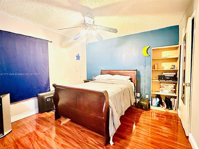 bedroom featuring ceiling fan, wood-type flooring, and a textured ceiling