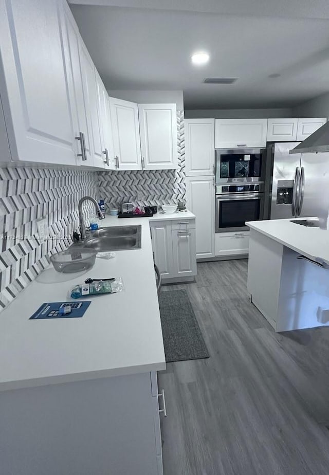 kitchen with stainless steel fridge, white cabinetry, dark wood-type flooring, and sink