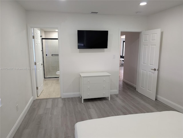 bedroom with ensuite bathroom and light hardwood / wood-style floors