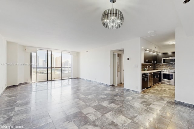 unfurnished living room featuring sink and a notable chandelier