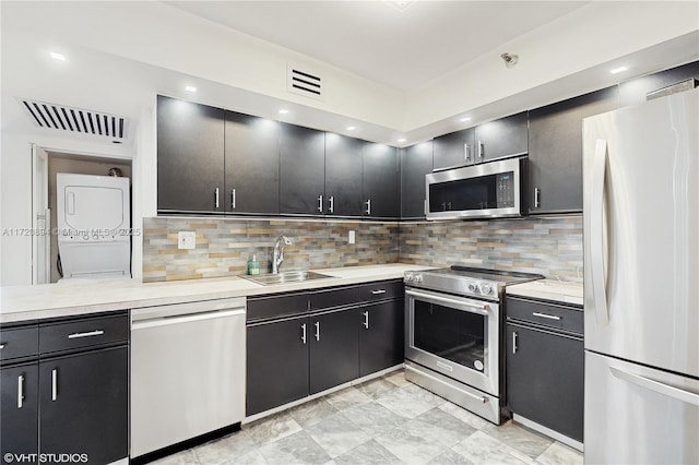 kitchen with tasteful backsplash, stainless steel appliances, sink, and stacked washer / drying machine