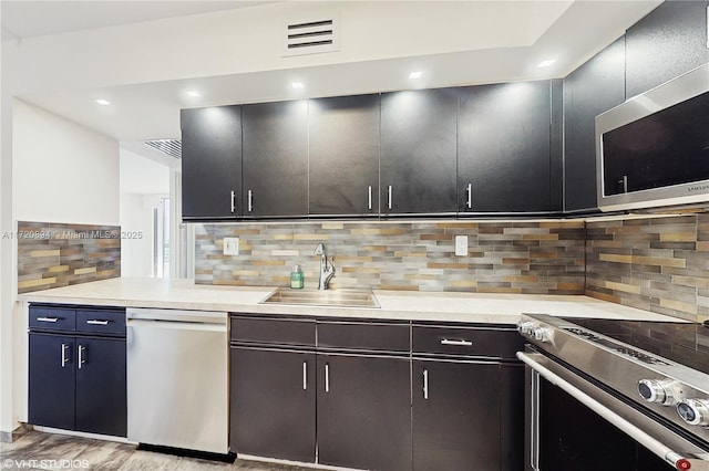 kitchen featuring stainless steel appliances, sink, light hardwood / wood-style flooring, and backsplash