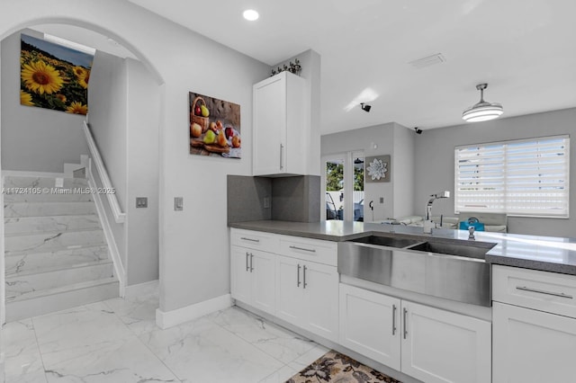 kitchen with sink, a healthy amount of sunlight, white cabinets, and backsplash