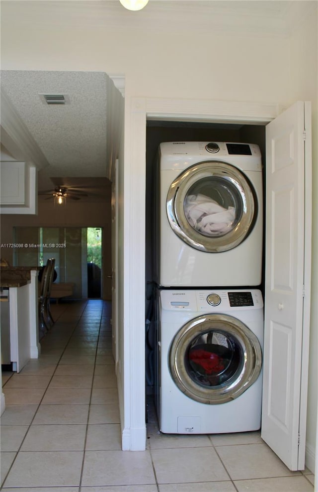 washroom featuring visible vents, laundry area, light tile patterned flooring, and stacked washer / drying machine