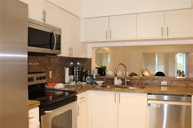 kitchen featuring stainless steel appliances, stone countertops, white cabinetry, and a sink