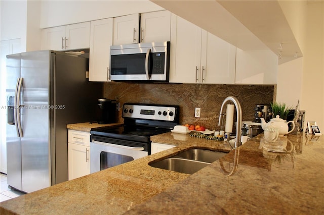 kitchen featuring a sink, white cabinetry, light stone countertops, decorative backsplash, and stainless steel appliances