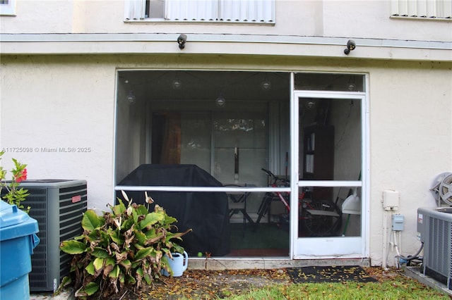 doorway to property with central air condition unit and stucco siding