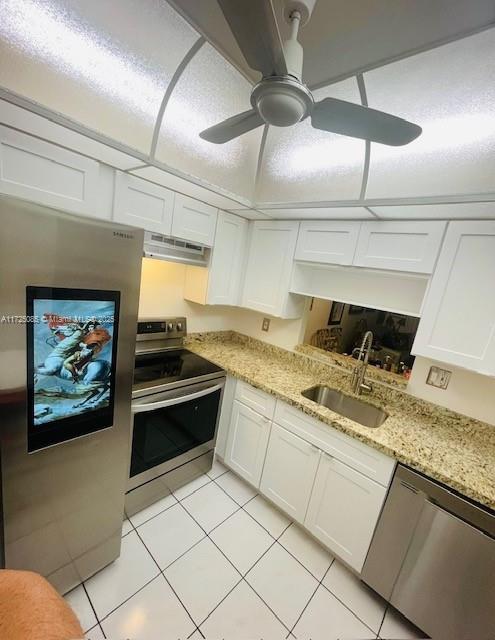 4441 NW 16th St Unit J311, Lauderhill, FL 33313 - kitchen with appliances with stainless steel finishes, a sink, under cabinet range hood, light tile patterned floors, and white cabinetry