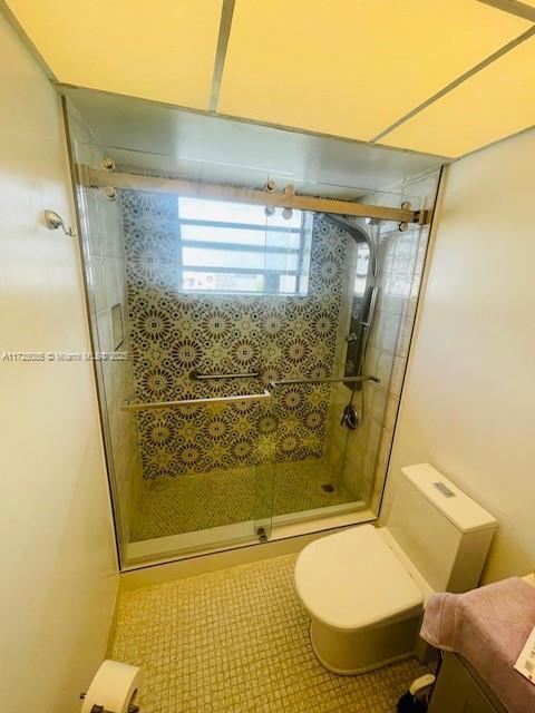 bathroom featuring tile patterned flooring, an enclosed shower, and toilet