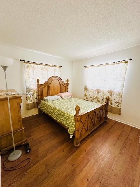 4441 NW 16th St Unit J311, Lauderhill, FL 33313 - bedroom with dark wood-type flooring, a textured ceiling, multiple windows, and baseboards