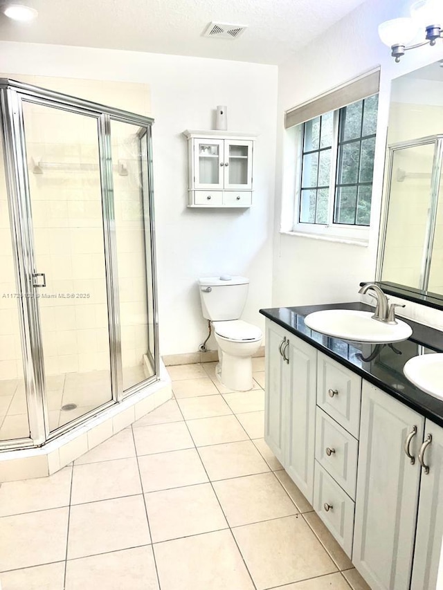 bathroom featuring tile patterned floors, vanity, toilet, and a shower with shower door