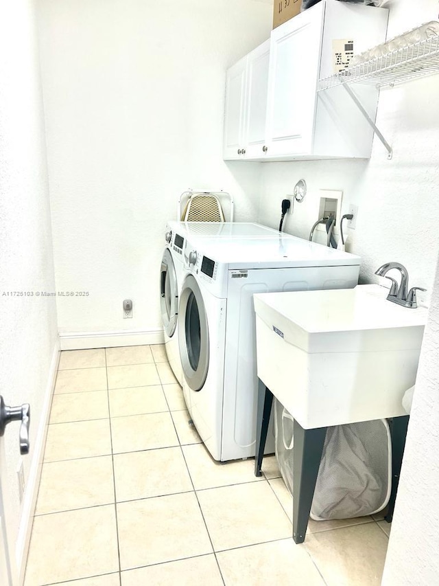 washroom with washer and dryer, sink, light tile patterned floors, and cabinets