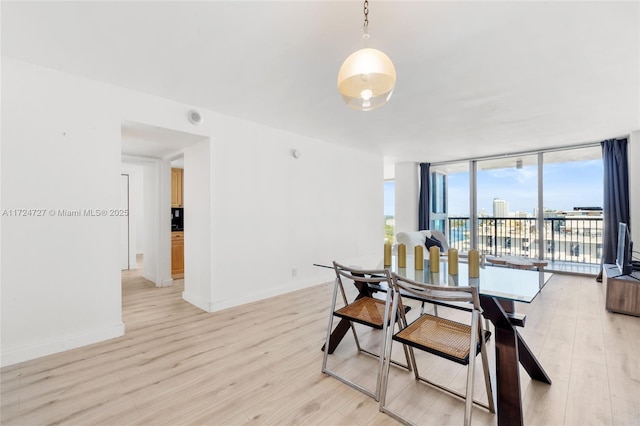 dining room featuring a wall of windows and light hardwood / wood-style floors