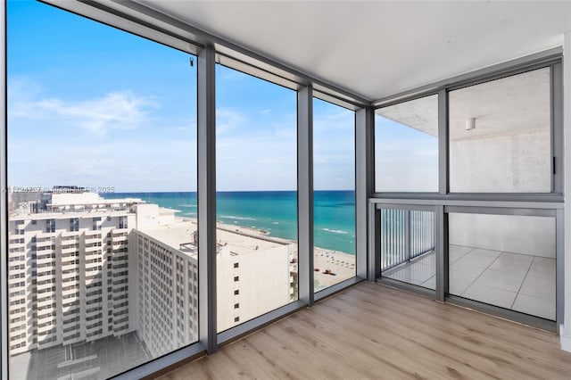 unfurnished sunroom with a water view and a view of the beach