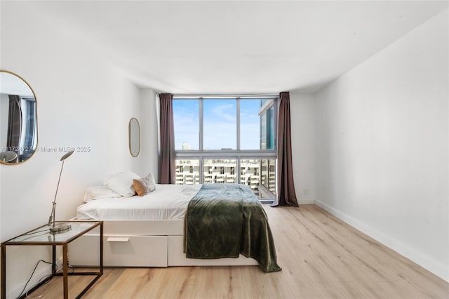 bedroom with expansive windows and light wood-type flooring