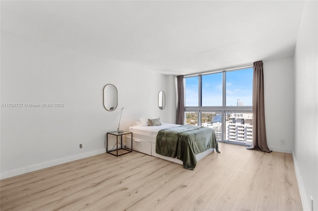 bedroom featuring a wall of windows and light hardwood / wood-style floors