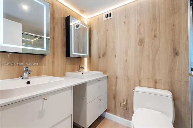 bathroom with wooden walls, vanity, and toilet