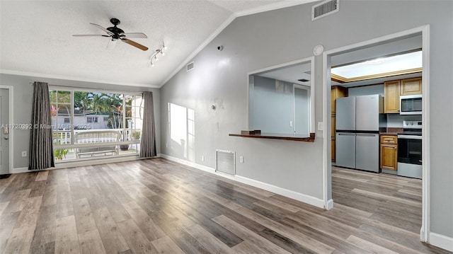 unfurnished living room featuring a textured ceiling, vaulted ceiling, light hardwood / wood-style flooring, crown molding, and ceiling fan