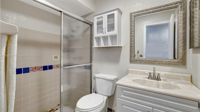 bathroom with toilet, a tile shower, and vanity