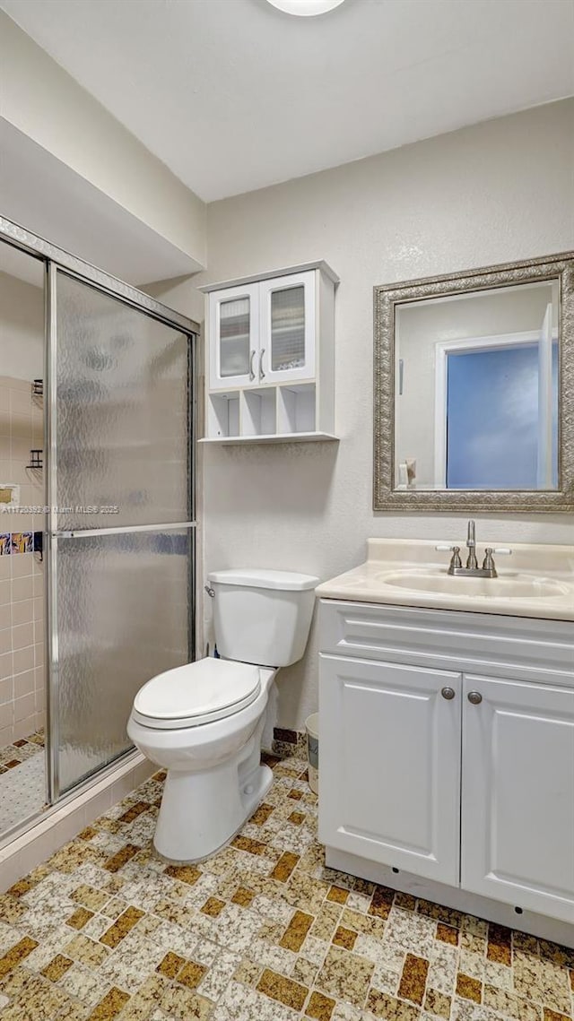 bathroom with a shower with door, vanity, and toilet