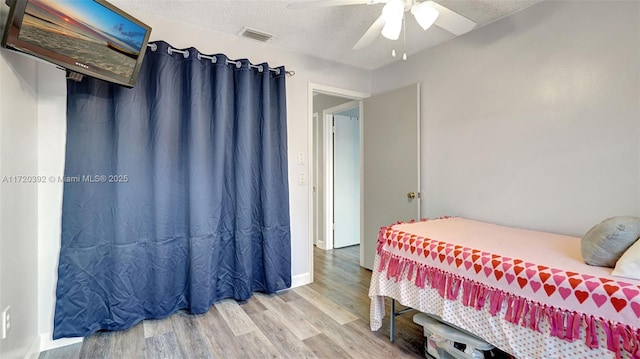 bedroom with ceiling fan, a textured ceiling, and hardwood / wood-style flooring