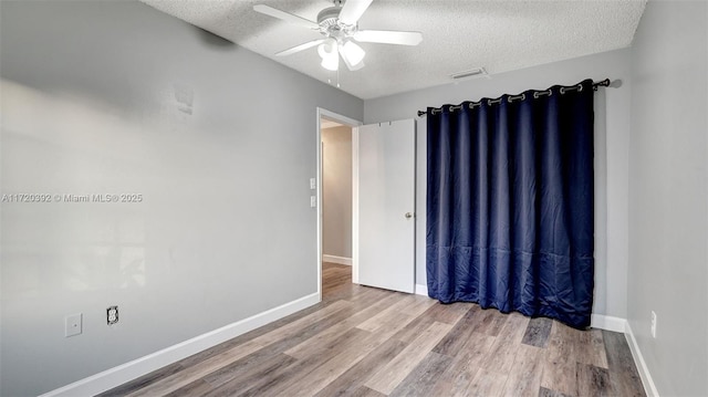 spare room featuring a textured ceiling, ceiling fan, and wood-type flooring