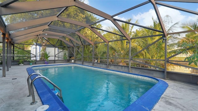 view of pool with a lanai, a patio area, and a storage shed