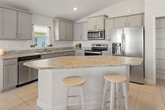 kitchen with a breakfast bar, sink, stainless steel appliances, and vaulted ceiling