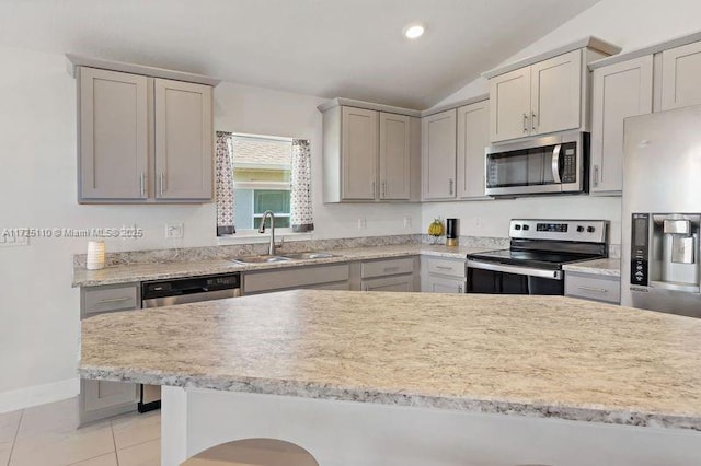 kitchen featuring sink, vaulted ceiling, gray cabinets, light tile patterned floors, and stainless steel appliances