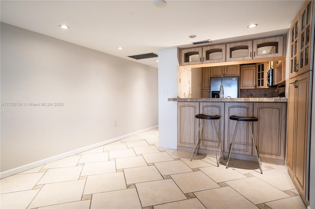 kitchen with tasteful backsplash, kitchen peninsula, stainless steel fridge with ice dispenser, and a breakfast bar area