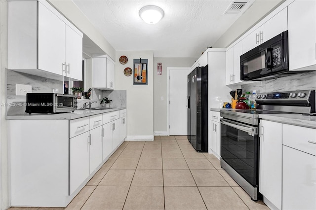 kitchen with sink, light tile patterned floors, white cabinetry, and black appliances