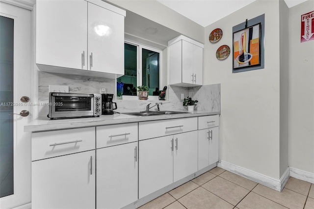 kitchen featuring sink, white cabinetry, and light tile patterned flooring