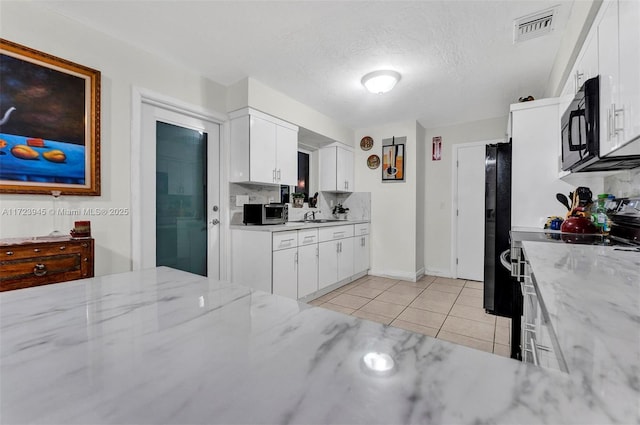 kitchen with black appliances, white cabinetry, and light stone countertops