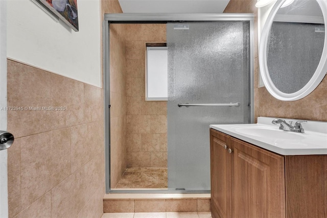 bathroom featuring tile walls, walk in shower, vanity, and tile patterned floors