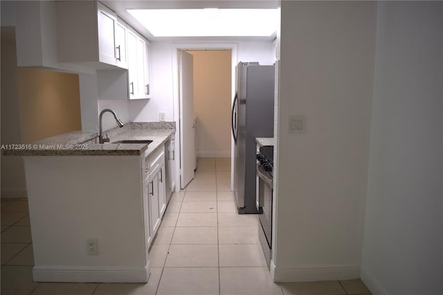 kitchen featuring white cabinets, sink, light tile patterned floors, appliances with stainless steel finishes, and light stone counters