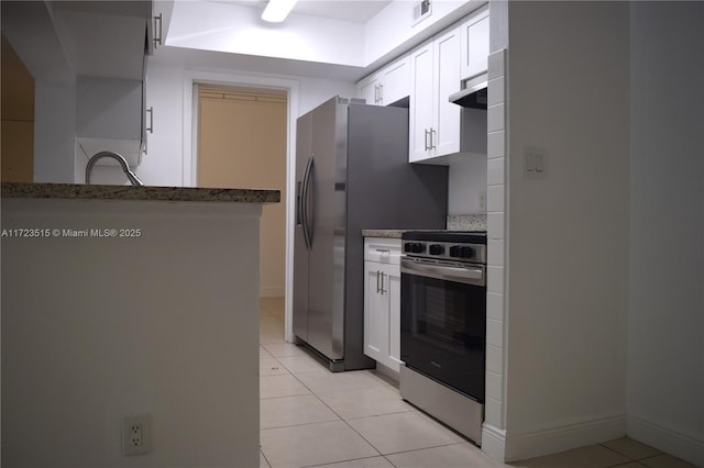 kitchen featuring light tile patterned floors, stainless steel appliances, white cabinetry, and dark stone countertops