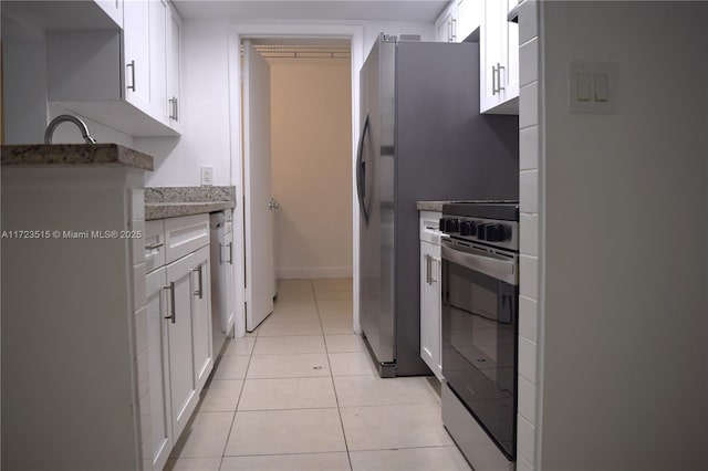 kitchen featuring electric stove, white cabinetry, light tile patterned floors, and light stone countertops