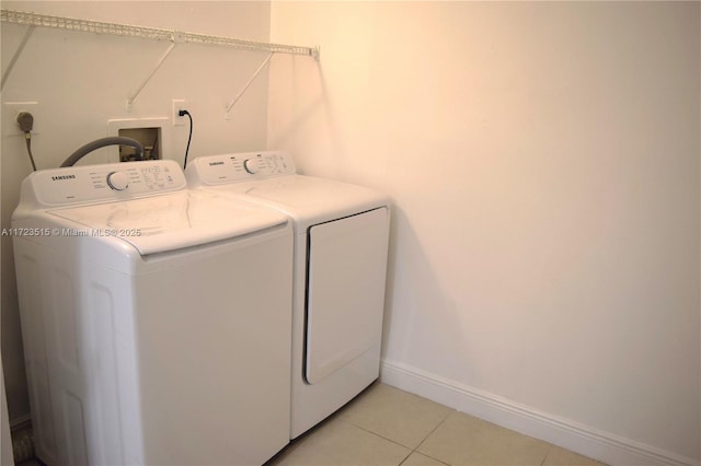 laundry area with washing machine and clothes dryer and light tile patterned floors