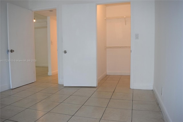 interior space featuring a spacious closet, light tile patterned floors, and a closet