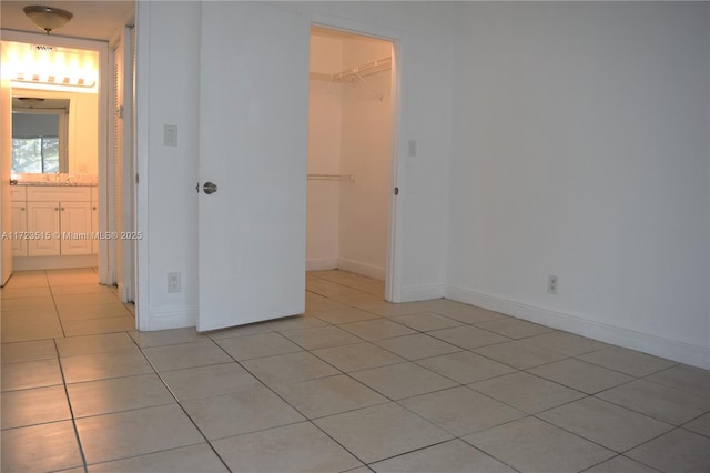 unfurnished bedroom featuring a walk in closet, a closet, and light tile patterned flooring