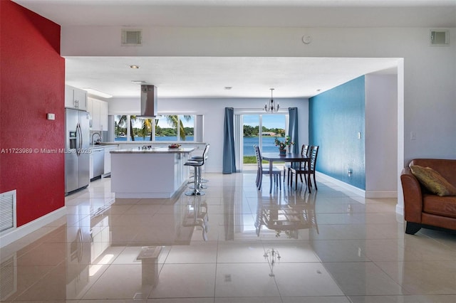 kitchen featuring an inviting chandelier, white cabinets, light tile patterned floors, appliances with stainless steel finishes, and decorative light fixtures