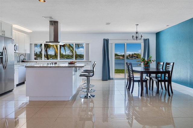 kitchen with white cabinetry, a center island, hanging light fixtures, stainless steel appliances, and island range hood