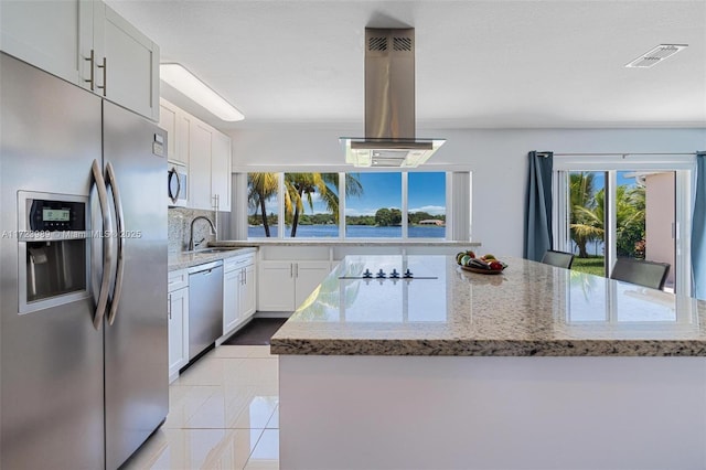 kitchen featuring island exhaust hood, a center island, white cabinets, and appliances with stainless steel finishes