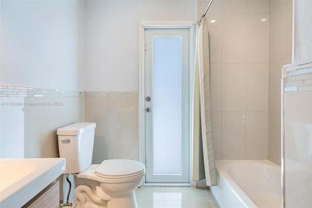 full bathroom featuring shower / bathtub combination with curtain, tile patterned flooring, toilet, vanity, and tile walls