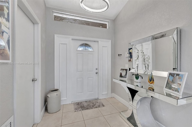 foyer entrance with lofted ceiling and light tile patterned flooring