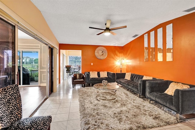 tiled living room featuring lofted ceiling, ceiling fan, plenty of natural light, and a textured ceiling