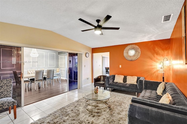 living room with ceiling fan, light tile patterned floors, a textured ceiling, and vaulted ceiling