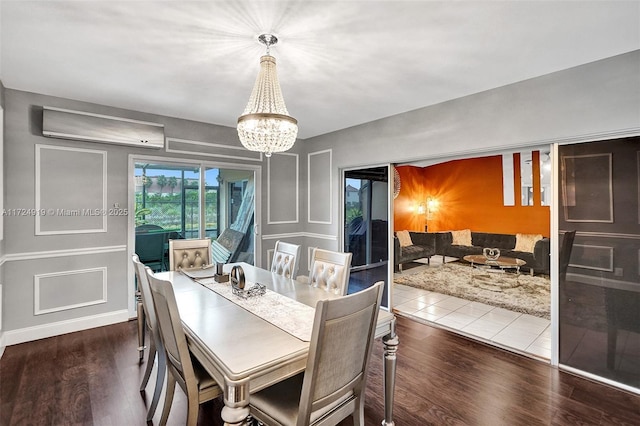 dining room featuring wood-type flooring, a wall unit AC, and a notable chandelier