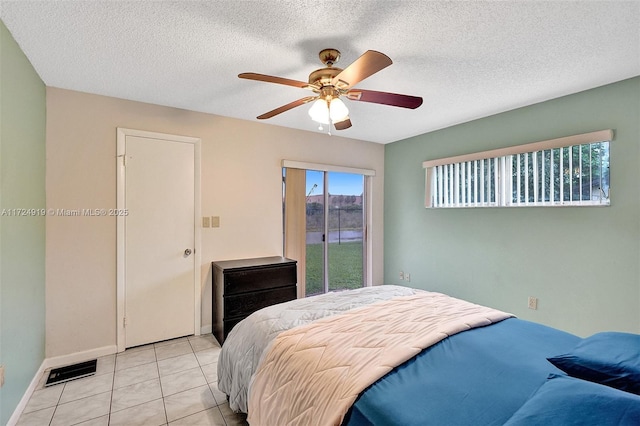 bedroom with ceiling fan, light tile patterned floors, a textured ceiling, and access to outside